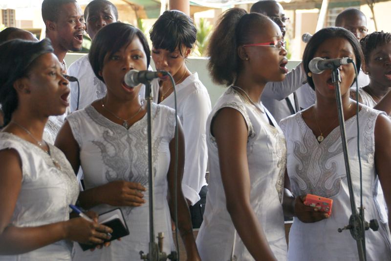 Choir singers in white performing at microphones